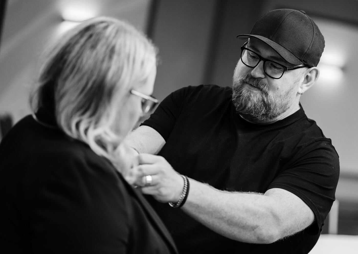 Black and white photo of a crew member clipping a microphone to an interviewee's jacket