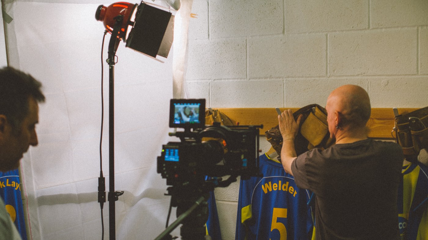 A cinema camera and a red tungsten light set up on a rail of Selco football shirts printed with trade names including Welder, during the Sky Sports ident shoot